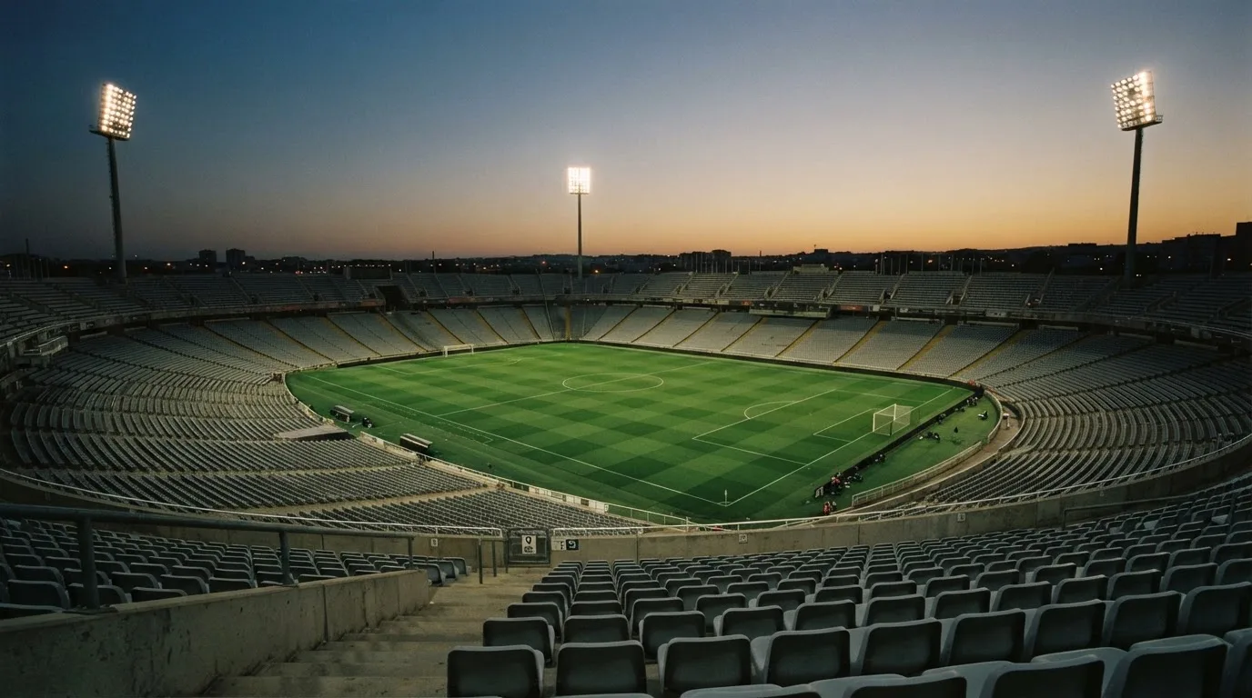 An empty football stadium with floodlight masts at dusk