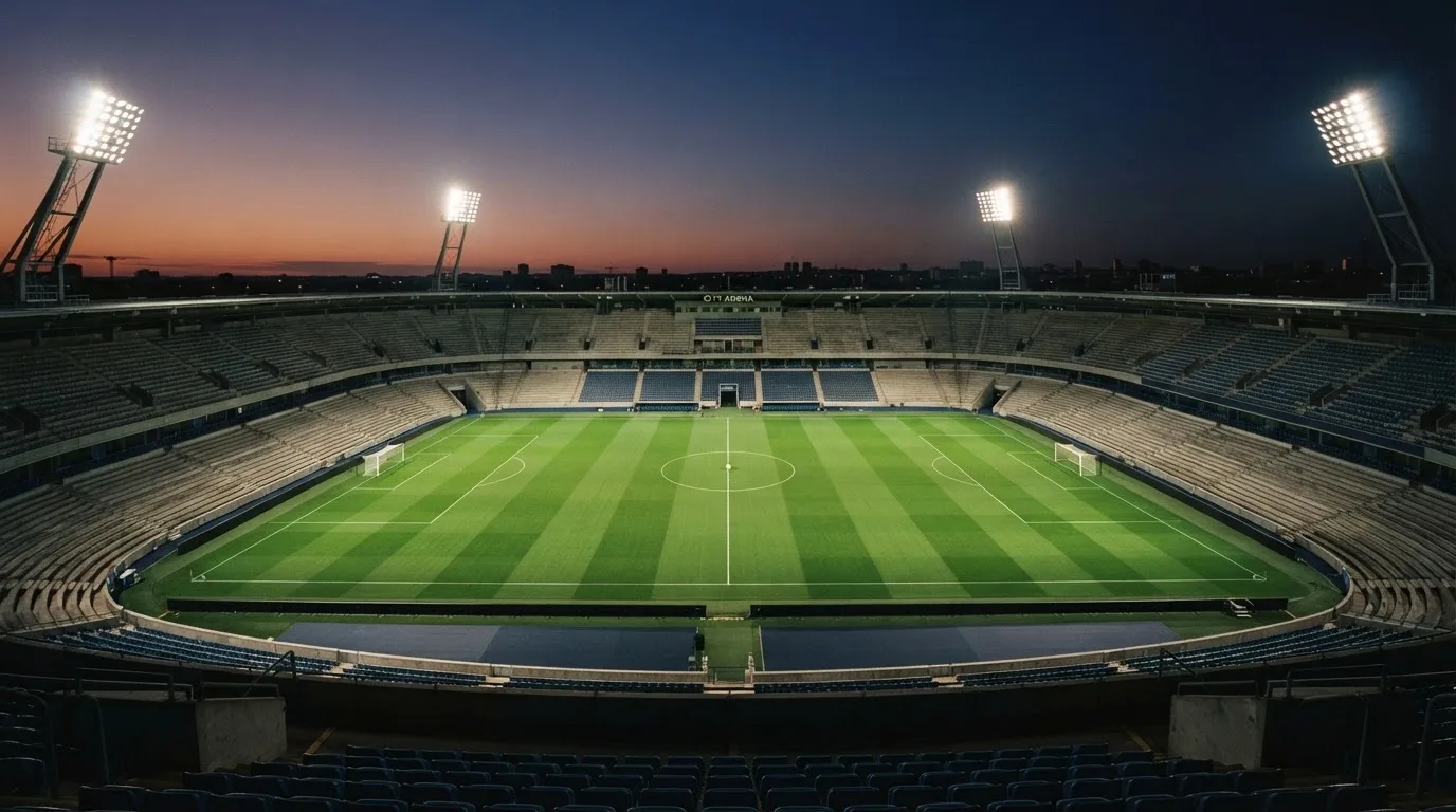 An empty football stadium with floodlight masts at dusk