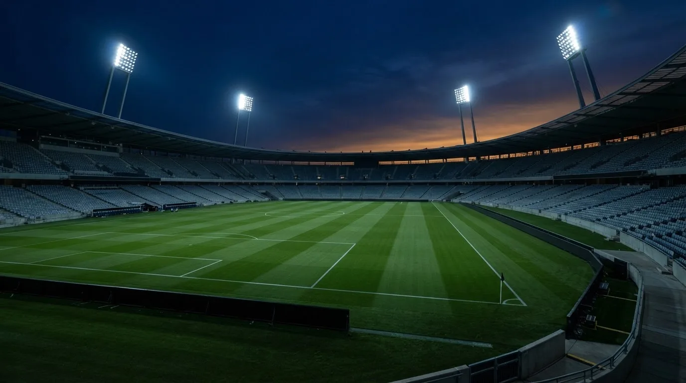 An empty football stadium with floodlight masts at dusk