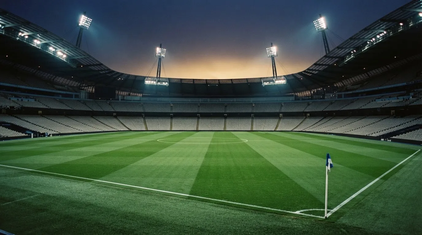An empty football stadium with floodlight masts at dusk