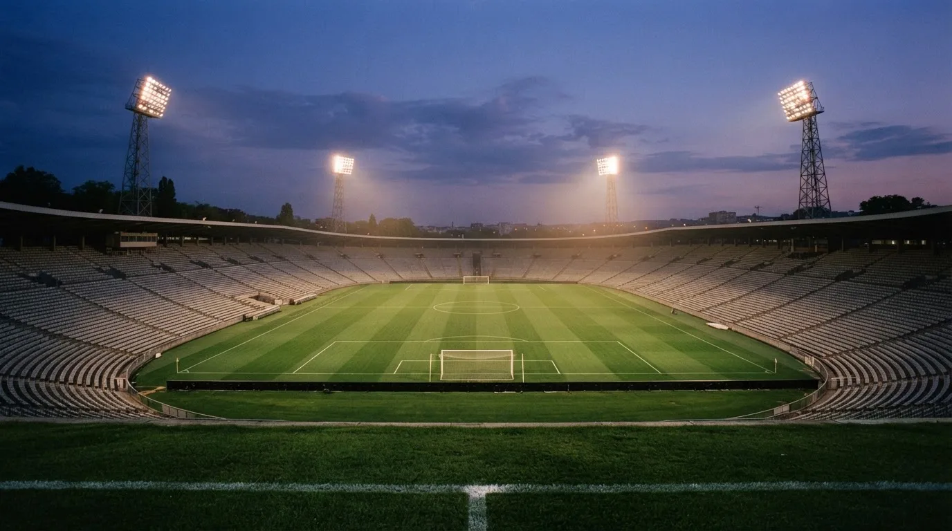 An empty football stadium with floodlight masts at dusk
