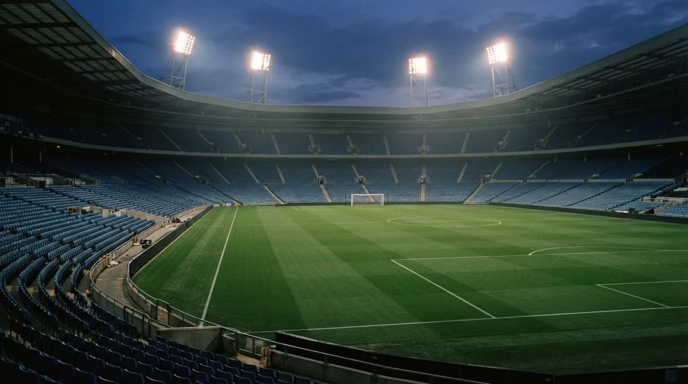 An empty football stadium with floodlight masts at dusk