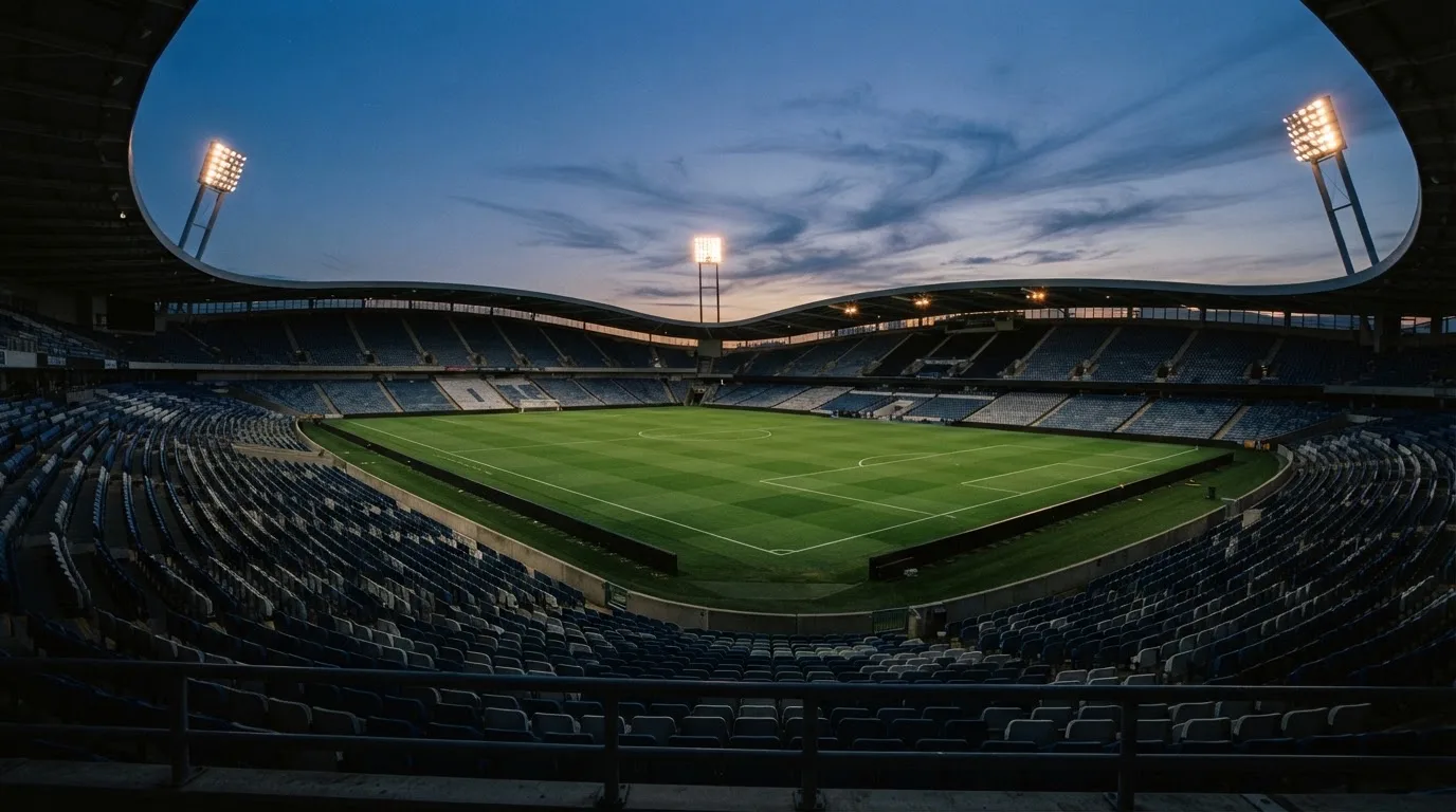 An empty football stadium with floodlight masts at dusk
