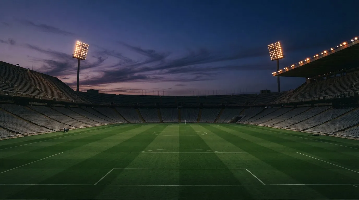 An empty football stadium with floodlight masts at dusk