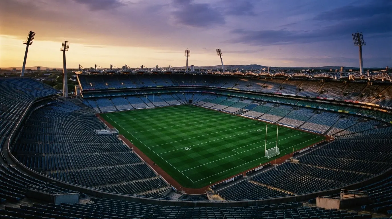 An empty football stadium with floodlight masts at dusk