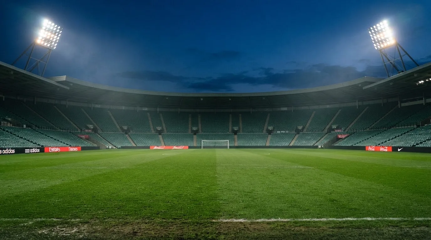 An empty football stadium with floodlight masts at dusk