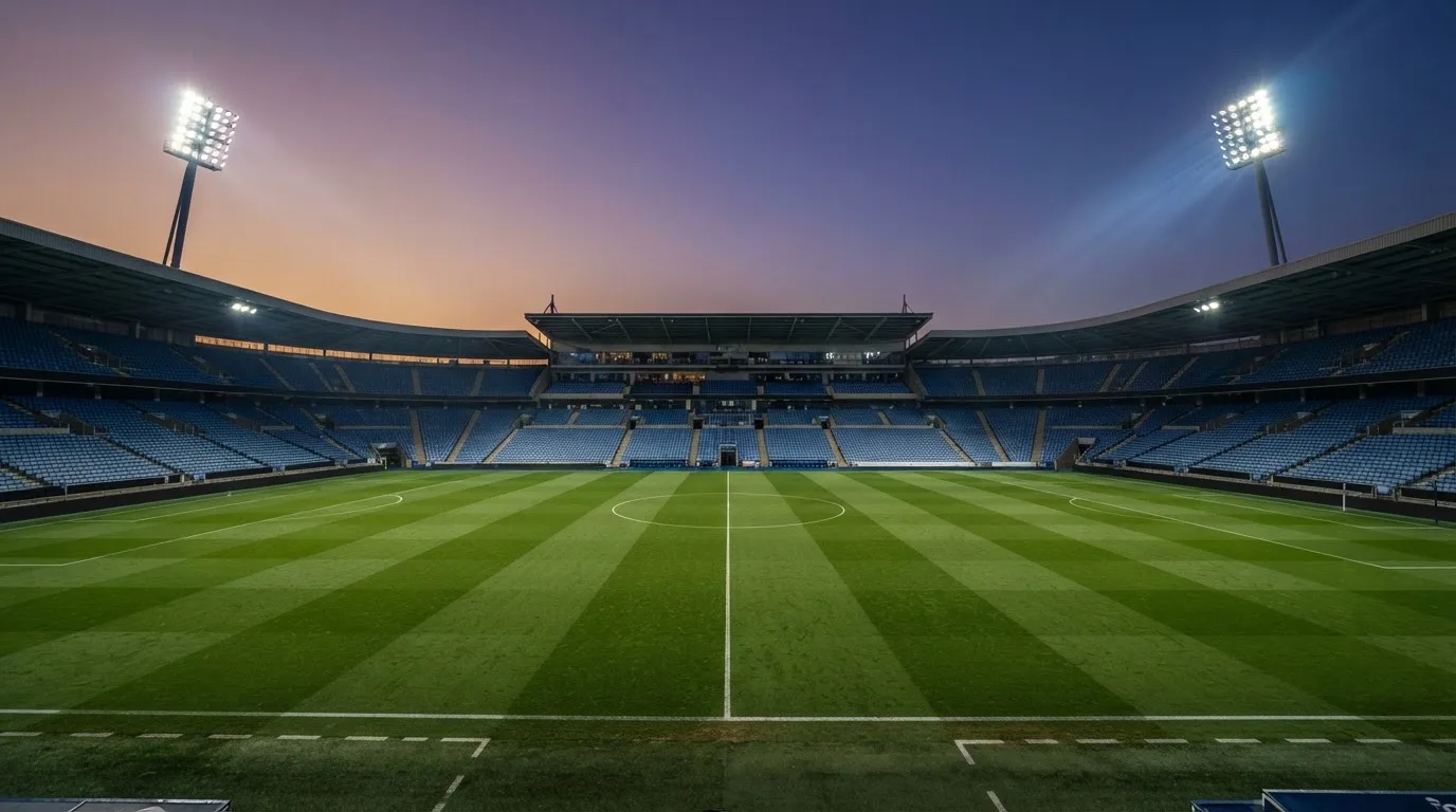 An empty football stadium with floodlight masts at dusk